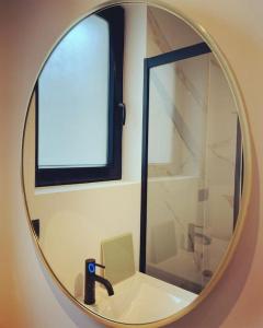 einen Badezimmerspiegel mit einem Waschbecken und einem Fenster in der Unterkunft Sea5 @ Nieuwpoort! Penthouse bij zee en winkels in Nieuwpoort