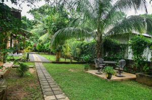 un jardín con un banco y una palmera en Clay House, en Udawalawe