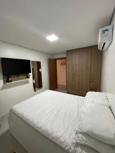 a bedroom with a white bed and a flat screen tv at Apartamento em Torres in Torres