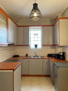 kuchnia z białymi szafkami, umywalką i oknem w obiekcie Filoxenia - Ολόκληρο διαμέρισμα w mieście Wolos