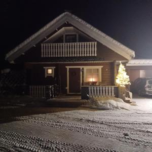 a house with a christmas tree in the snow at Villa Bear's in Rovaniemi