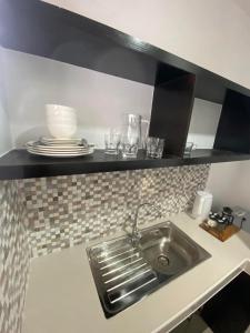 a kitchen counter with a sink and a shelf at Ma Lourdes Inn- Washington Street in Palompon