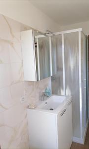 La salle de bains est pourvue d'un lavabo blanc et d'un miroir. dans l'établissement La dimora degli Angeli, à Moggio