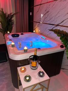 een hot tub met een fles champagne en wijnglazen bij NUITS D'HERMES & Spa in Chalon-sur-Saône