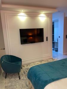 a bedroom with a bed and a chair and a television at NUITS D'HERMES & Spa in Chalon-sur-Saône