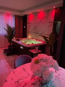 a room with a tub with a table and flowers at NUITS D'HERMES & Spa in Chalon-sur-Saône