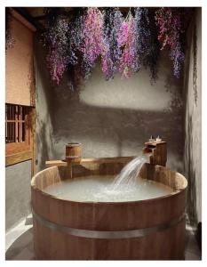 una bañera de madera con una fuente con flores colgando de ella en MAYU Bangkok Japanese Style Hotel en Bangkok