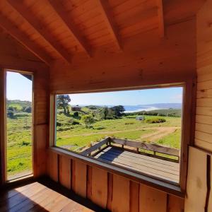 a window in a cabin with a view of a field at PUESTA DE SOL in Cobquecura