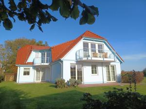 ein großes weißes Haus mit orangefarbenem Dach in der Unterkunft An den Boddenwiesen I in Wustrow