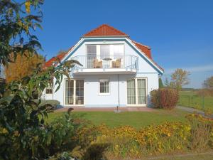 ein weißes Haus mit einem Balkon auf einem Hof in der Unterkunft An den Boddenwiesen I in Wustrow