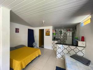 a bedroom with a yellow bed and a kitchen at Casa na Orla - Praia de Gaibu! in Cabo de Santo Agostinho