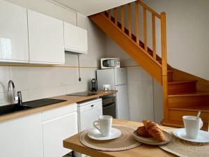 a kitchen with a table with two cups and croissants on it at Le Cosy Troyen secteur calme 4 personnes parking privé in Troyes