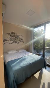 Pousada Low Tide maresias في ماريسياز: غرفة نوم مع سرير مع لوحة للأسماك على الحائط