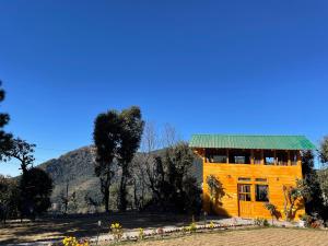 a wooden house with a green roof in a field at Bagar Trails in Nainital