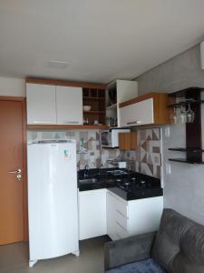 a kitchen with white cabinets and a white refrigerator at Flat- maraca bech residence 2 in Ipojuca