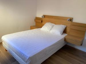 a bedroom with a white bed with a wooden headboard at Spacieux F3 Port Leucate in Leucate