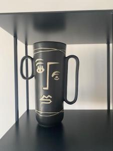 a black mug with a face on a shelf at APPARTEMENT REFAIT A NEUF, IDEALEMENT SITUÉ in La Baule