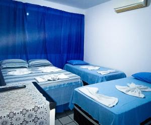 3 camas en una habitación con cortinas azules en Pousada Tô Em Casa!, en João Pessoa