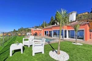 un patio con sillas blancas y una palmera en Casa Yaneric en Tijarafe