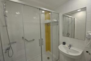 ein Bad mit einer Dusche und einem Waschbecken in der Unterkunft Hotel Búzio in Sines
