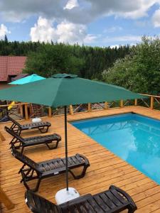 eine Terrasse mit Stühlen und einem Sonnenschirm neben einem Pool in der Unterkunft Шервуд in Myta