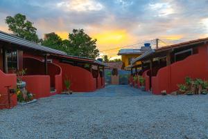a pathway between two red buildings with a sunset in the background at Kalug - Chalé Chão de Trancoso Studios in Trancoso