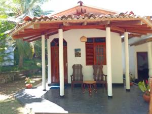 una pequeña casa con pérgola y 2 sillas en Peacock Garden, en Tangalle