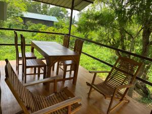 a table and chairs on a porch with a view of a forest at mango villa wilpattu in Nekattegama