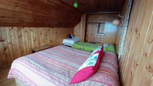 een slaapkamer met een bed in een houten hut bij Hostal Casa Damasco in Ancud