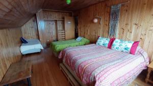een slaapkamer met 2 bedden in een houten hut bij Hostal Casa Damasco in Ancud