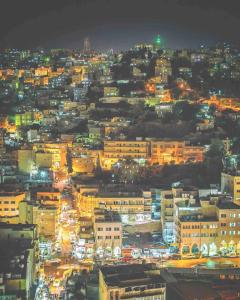una ciudad iluminada por la noche con edificios en Khirfan Crown Houses -downtown, en Amán