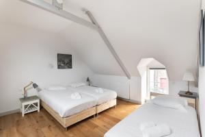 Duas camas num quarto com paredes brancas e pisos em madeira em Le Phare de la Fenêtre em Cancale