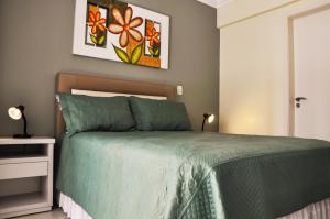 a bedroom with a bed with a green comforter at Ótima Localização!!! Apartamento De Frente No Centro De Capão Da Canoa in Capão da Canoa