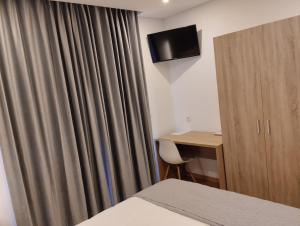 a hotel room with a curtain and a desk and a television at AL Recanto do Sol in Torres Novas