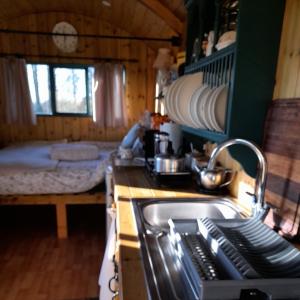 una cocina con fregadero y una cama en una habitación en Lower Haven Shepherds Hut, en Bath