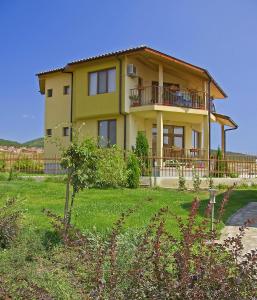 a yellow house with a balcony and a yard at Montemar Villas in Sunny Beach