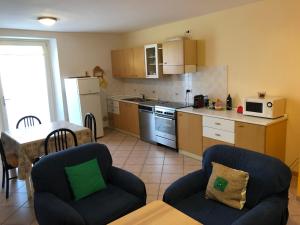 a kitchen with two chairs and a table and a kitchen with a microwave at Appartamento Rosa in Coredo