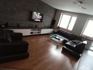 a living room with black furniture and a flat screen tv at Apartament 24 dwie sypialnie in Płock
