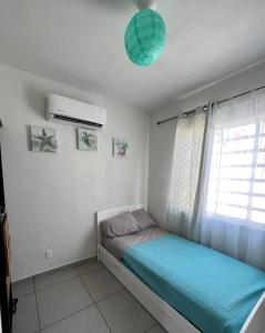 a small bed in a room with a window at Casa Aqua, con alberca y club de playa in Barra Vieja