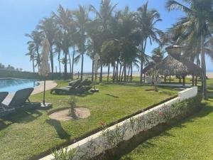 a resort with a swimming pool and palm trees at Casa Aqua, con alberca y club de playa in Barra Vieja