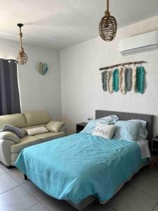 a bedroom with a blue bed and a couch at Casa Aqua, con alberca y club de playa in Barra Vieja