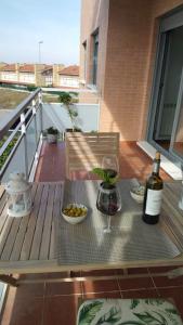 Una botella de vino sentada en una mesa en un balcón en Coqueto apartamento en urbanización piscina y golf, en Cirueña