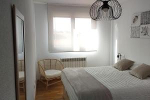 1 dormitorio con 1 cama, 1 silla y 1 ventana en Coqueto apartamento en urbanización piscina y golf, en Cirueña