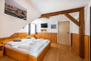 - une chambre dotée d'un lit avec des draps blancs dans l'établissement Penzion Černý vlk, à Kvilda
