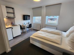 a bedroom with a bed and a kitchen and a desk at Davin City Aparments - Self-Check-In in Hamburg