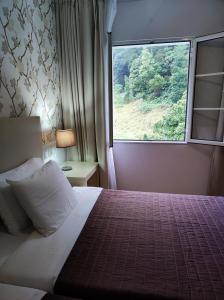 a bedroom with a bed with a large window at Vista Do Vale in Furnas