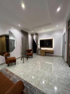 a living room with a tv and a couch and chairs at Bricks Residence in Lekki
