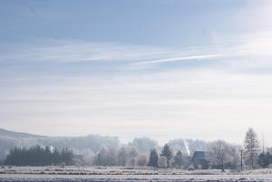 a snow covered field with a house in the background at Dom z widokiem - Wilkanów 184 in Wilkanów