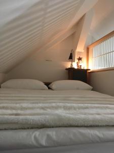 ein weißes Bett in einem Zimmer mit Fenster in der Unterkunft Erdre Rivière Climatisé in La Chapelle-sur-Erdre