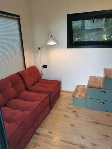 a living room with a red couch and a table at Tiny House in Garden with Sea View in Karamusal